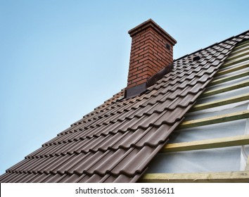 Roof under constructions with lots of tile and red brick chimney