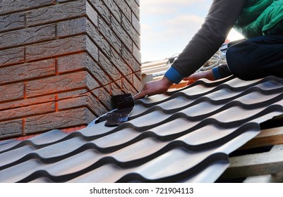 Roofer builder worker attach metal sheet to the chimney. Unfinished roof construction. - Shutterstock ID 721904113