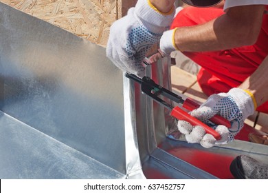 Roofer builder worker finishing folding a metal sheet using special pliers with a large flat grip