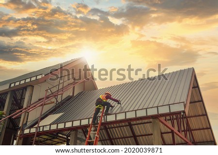 Roofer Construction worker install new roof,Roofing tools on during sunset,Electric drill used on new roofs with Metal Sheet.