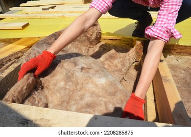 Roofer contractor laying mineral wool insulation on house roof for energy saving. Mineral wool insulation of the roof. Insulating the roof with mineral wool will help prevent heat loss. - Shutterstock ID 2208285875