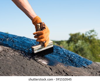 Roofer cover the concrete base, polymer modified bitumen waterproofing primer. A worker brushes cover concrete, bitumen-rubber primer. - Shutterstock ID 591510545