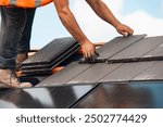 Roofer Installing New Slate Tiles on Residential Roof Under Blue Sky