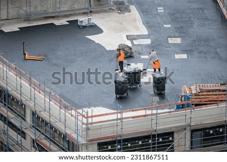 Roofer painting flat roof of a commercial building.	