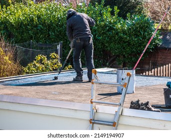 Roofer rolls a tar sheet with bitumen on a flat roof