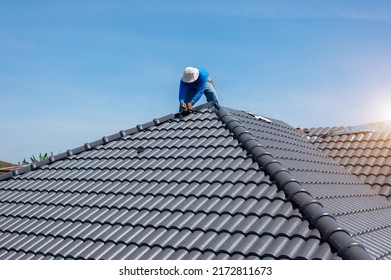 Roofer at work, installing clay roof tiles,Construction roofer installing roof tiles at house building site - Shutterstock ID 2172811673