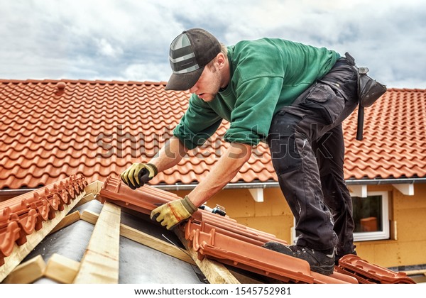 Roofer at\
work, installing clay roof tiles,\
Germany