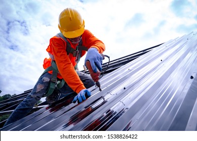 Roofer working on roof structure of building on construction site,Roofer using air or pneumatic nail gun and installing Metal Sheet on top new roof.