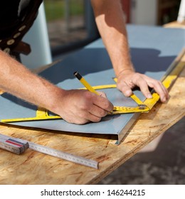Roofer working with a protractor to make markings on a metal sheet