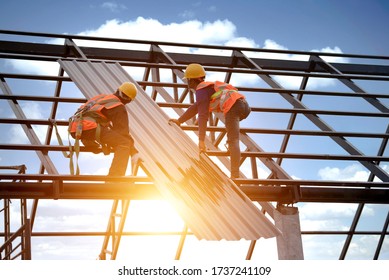 Roofer works on the roof structure of a building at a construction site. Roofer uses an air gun or air gun and install Metal Sheet on a new roof in Asia.