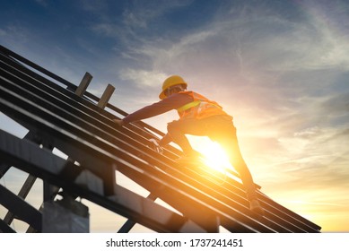 Roofer works on the roof structure of a building at a construction site. Roofer uses an air gun or air gun and install Metal Sheet on a new roof in Asia.