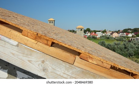 Roofing construction. A close-up of a roof under construction on the stage of roof sheathing, installed OSB roof deck over timber planks and wood braces. - Shutterstock ID 2048469380