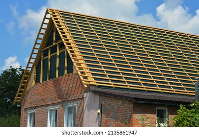 Roofing construction and renovation. Installing a new roof underlay and timber battens on a gable roof with a large roof window before tiles installation. - Shutterstock ID 2135861947