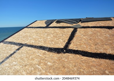 Roofing construction and waterproofing. A close-up of OSB roof deck, roof sheathing with hot rubberized asphalt, bitumen, tar waterproofing before asphalt shingles installation. - Shutterstock ID 2048469374