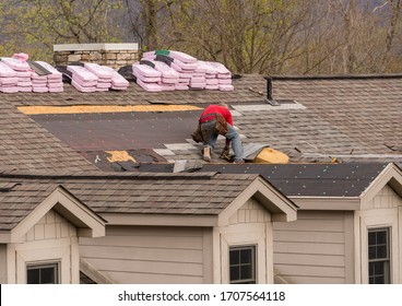 Roofing Contractor Removing The Old Tiles Before Replacing With New Shingles On A Townhouse Roof