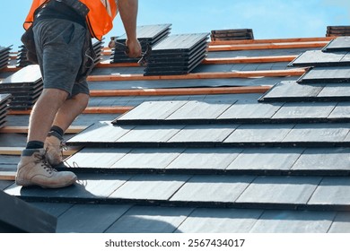 Roofing project in progress with worker installing slate tiles on a sunny day