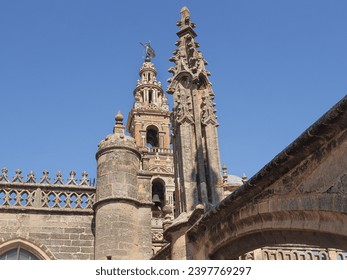 Rooftop of the Catedral de Sevilla (Gothic church of Saint Mary of the See). Stone masonry building with buttresses, towers and iconic Moorish minaret or bell tower La Giralda. Spanish architecture. - Powered by Shutterstock