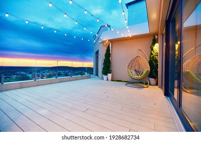 Rooftop Deck Patio Area With Hanging Chair And Lights On A Sunset