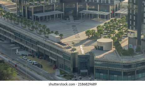 Rooftop Garden With Palms Near Entrance To Office Towers In Financial District Of Dubai City Evening Timelapse. Aerial View With Road And Parking