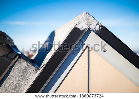 Rooftop hatch corner with waterproofing repair on metal flashing. Roof maintenance on skylight with a 2-ply SBS or modified bitumen roofing system and liquid membrane and granules. Selective focus.