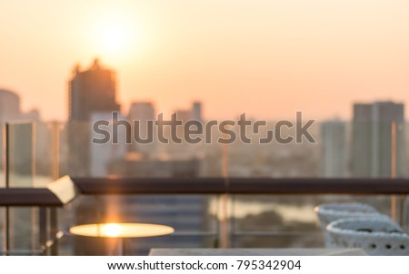 Rooftop party blur city view background from hotel balcony toward blurry restaurant bar dining table during happy hour romantic dinner with golden light evening sunset and sun flare