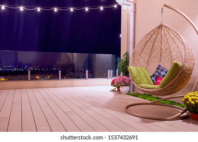 Rooftop Patio Area With Hanging Swing Chair And String Lights At Night