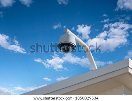 Rooftop security camera with cloudy sky.