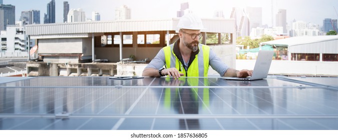 Rooftop solar power plant engineers sitting and examining photovoltaic panels. Concept of alternative energy and its service. Electrical and instrument technician use laptop to maintenance electric sy