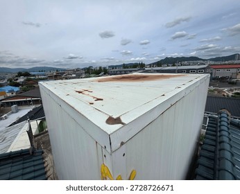 Rooftop structure with metal surface under cloudy sky

