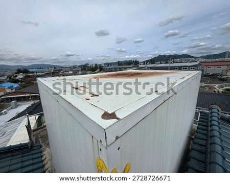 Rooftop structure with metal surface under cloudy sky

