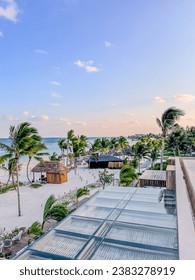 Rooftop view of the resort beach featuring palm trees, cabanas and the Gulf of Mexico at golden hour