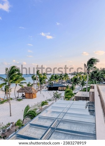 Rooftop view of the resort beach featuring palm trees, cabanas and the Gulf of Mexico at golden hour