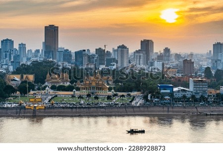 Rooftop view,looking across to the Riverside area of Cambodia's capital city.Sunset over Royal Palace and high rise buildings beyond, as a small boat drifts by towards the Mekong river. Stok fotoğraf © 