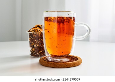 Rooibos tea in a transparent thermos mug on the table close-up. Visual for tea sample. Method of brewing and storage. Welding in a transparent teapot. Tea color, brewed citrus.
