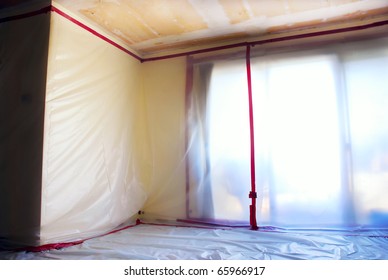 Room covered with clear plastic sheeting after asbestos abatement completed on popcorn ceiling