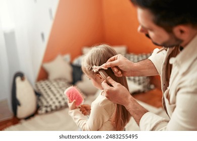 In a room filled with delightful decorations, a father lovingly braids his daughters hair, illustrating their strong bond and affectionate relationship. Happy father's day. - Powered by Shutterstock