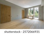 A room with a final finish in a private house. Unfurnished. Light laminate flooring, brown 
doors and access to the balcony.