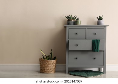 Room interior with grey chest of drawers near beige wall
