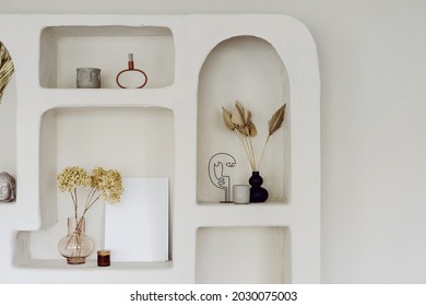 Room interior with wall design, decor at niche shelf. Modern home decoration, indoors apartment style in white. Vintage archs, exotic space of living room. Natural decorative elements.