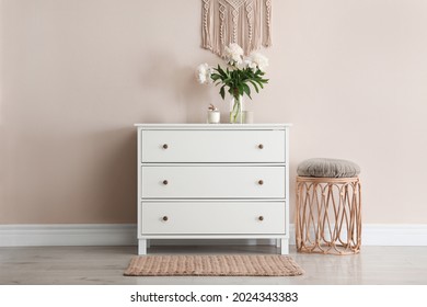 Room interior with white chest of drawers near beige wall