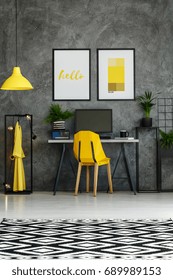 Room with metal desk, yellow accents, textured wall and mock-up posters