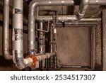 Room and pipes. Dark basement. Engineering communications. Heating pipes near brick walls. Pipeline into thermal insulation material. Basement with utilities. Room with sewer pipes.