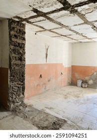 room in the process of remodeling or partial demolition. You can see a wall from which part of the finish has been removed, leaving the adobe bricks exposed in one of its corners.