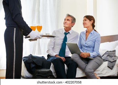 Room Service Bringing Drinks To Business Couple In A Hotel Room