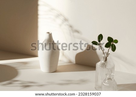 A room with various objects such as warm sunlight,
shadows of grass leaves, a vase on a table, and cups