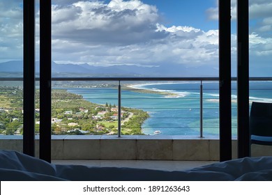 Room with a view through window and balcony railing to Plettenberg Bay, Keurboomsrivier and Indian Ocean, South Africa
