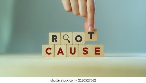 Root cause analysis concept. Define problems to find solution. Business problem solving.  Hand holds the wooden cubes with text ROOT CAUSE and magnifying glass icon on grey background,copy space. 