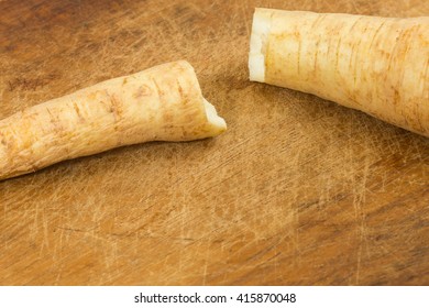 Root vegetables lying on a brown cutting board.