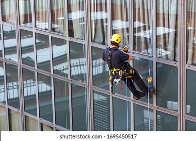 Rope access cleaner on a building. man in climbing equipment is repairing an office building