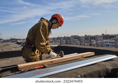 Rope access. A climber works on the roof of a house in the city. A construction worker works with a rope on the roof of a high-rise building in a metropolis.